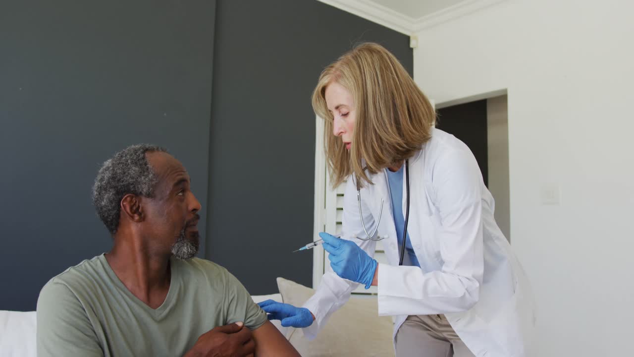 Caucasian senior female doctor giving vaccination to african american senior male patient