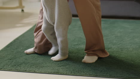 joyous baby making first steps with mom