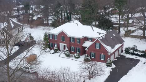 large colonial brick home covered in winter snow