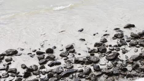 waves interacting with rocks on a sandy beach