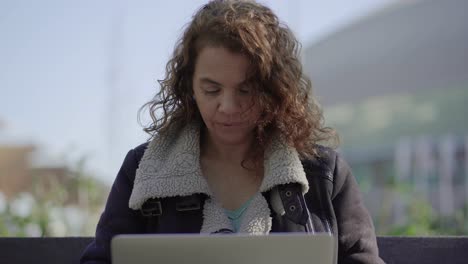 Mujer-Madura-Sonriente-Usando-Una-Computadora-Portátil-Al-Aire-Libre