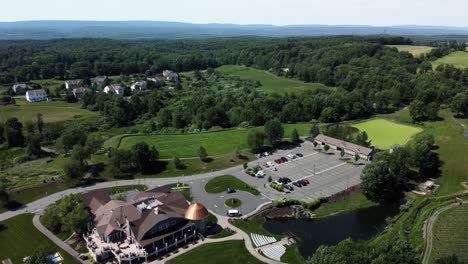 Drone-backward-movement,-aerial-view-of-a-banquet-house-for-celebrations-and-weddings,-surrounded-by-green-land-and-trees