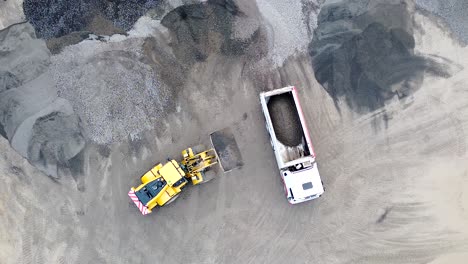 Truck-tipping-gravel-into-lorry-at-quarry