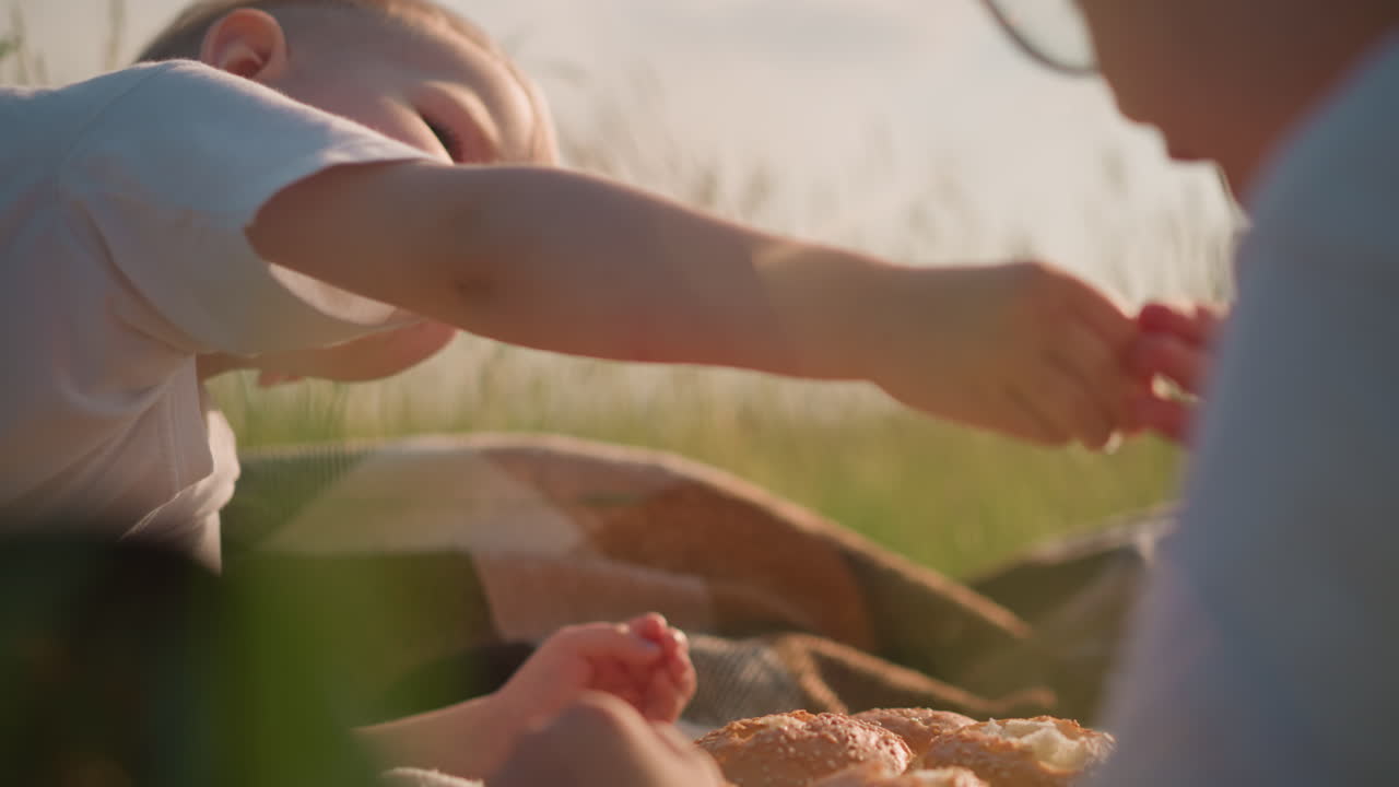 잔디에 앉아 을 나누고 있는 두 소년의 클로즈업  - 어린 소년은 친한 형에게  한 조각을 부드럽게 제공하여 형제 간의 유대와 보살의 순간을 포착합니다.