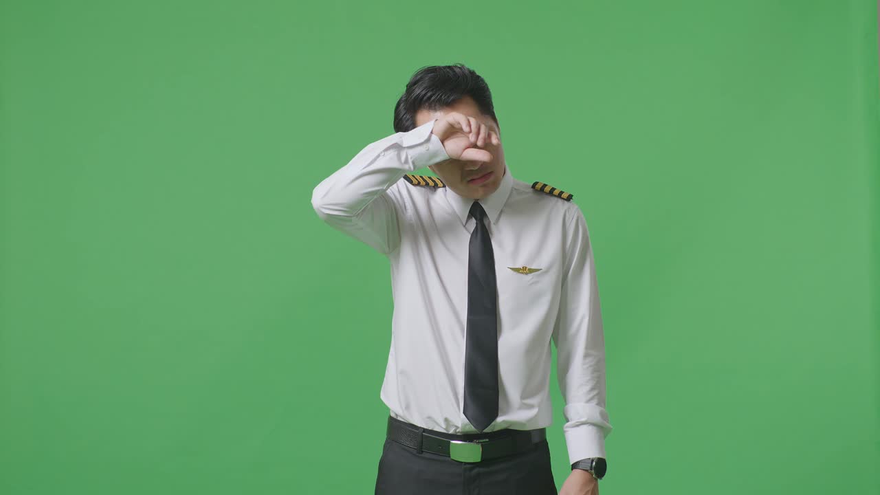 아시아인 조종사가 을 고 녹색 스크린 배경 스튜디오에 서서 피곤합니다.
