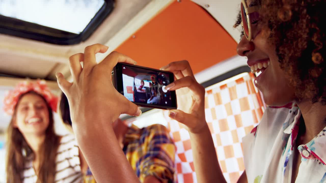 mujer tomando fotos de sus amigos con teléfono móvil 4k