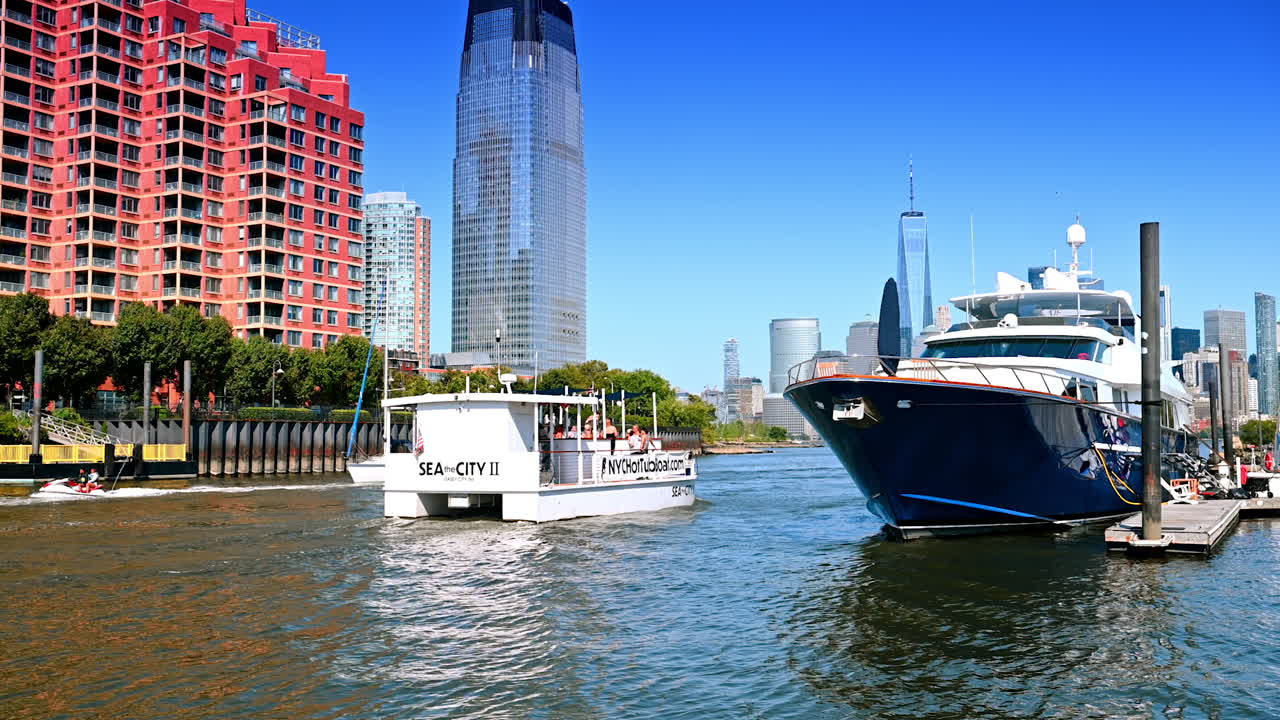 Jersey City, USA, 1 July 2025: Diverse boats move by the narrow part of the East River in Jersey City. Futuristic skyscrapers of Manhattan at backdrop