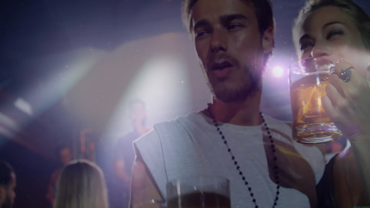 Male partygoer holding beer and woman sipping beer in nightclub with animated icons on stage lights