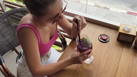 woman enjoying a purple cocktail at an outdoor cafe