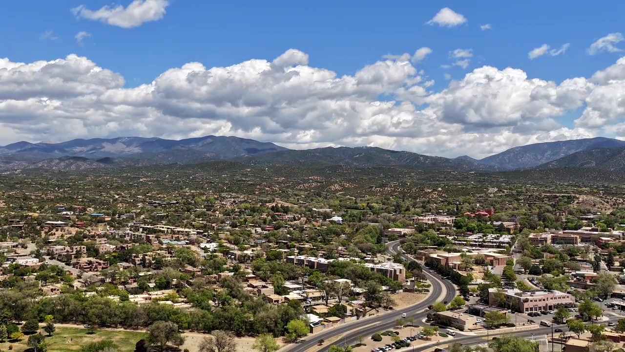 Un timelapse con drone in 4K cattura le nuvole primaverili in movimento e la luce dinamica sopra la parte alta di Santa Fe, Nuovo Messico. La vista aerea cinematografica mette in risalto le colline pedemontane di Sangre de Cristo e il paesaggio montano del sud-ovest.