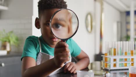 video of african american boy with magnifier doing experiments at home