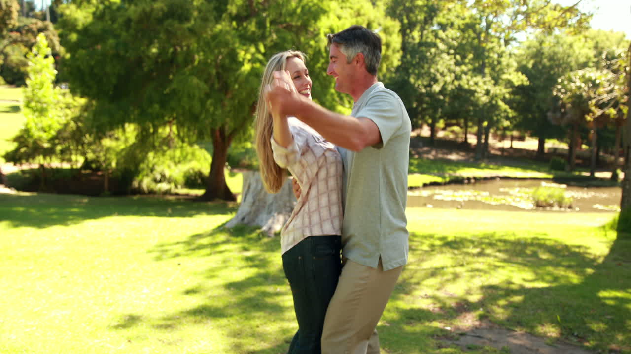 una pareja feliz bailando en el parque.