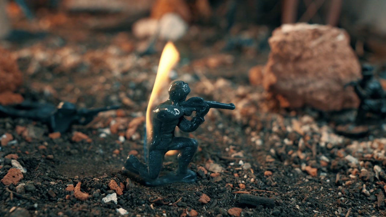 Small plastic soldier figure melting and burning in a war diorama. Symbolic concept of the horrors of war, conflict, and loss
