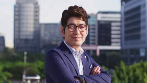 portrait of asian man crossing his arms while standing at corporate park