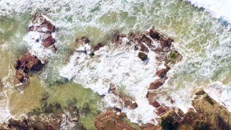 Olas-Rodando-Desde-La-Esquina-Derecha-Del-Marco-Hacia-Las-Rocas-Sedimentarias-Del-Océano-Pov-Drone-Turimetta-Beach-Sydney-Australia