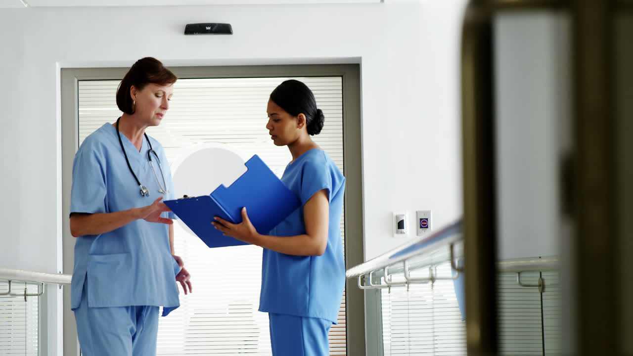 Nurse and doctor discussing over clipboard