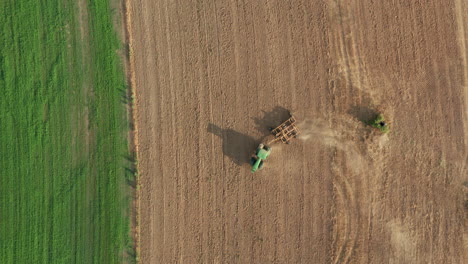 farming tractor on agricultural dirt field - aerial topdown drone view