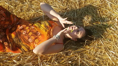 joven morena acostada en un campo de trigo a principios de verano mientras canta