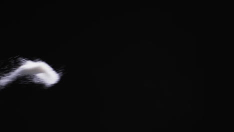 video of white sand grains thrown in air and copy space on black background