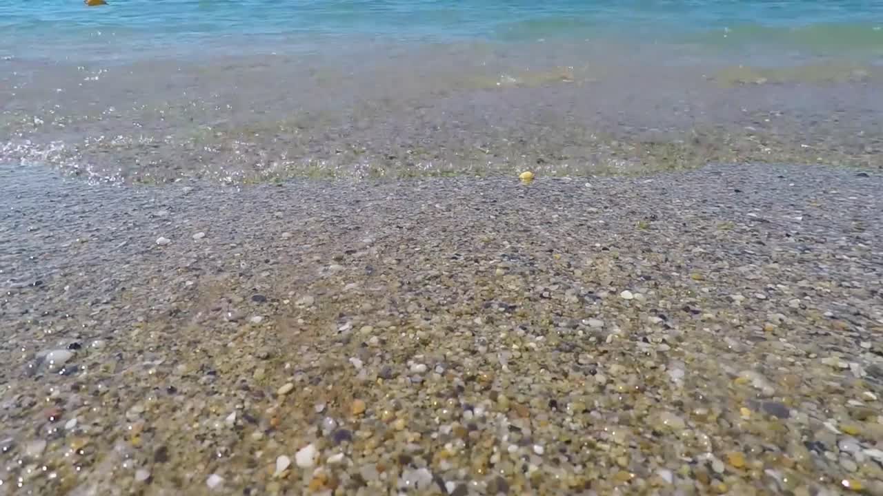 Waves of Mediterranean Sea rolling in sunshine to the sandy beach. Beautiful Turkish nature.Close-up shot of calming foamy water.Sea. Beach. Sand. Sky. The beach with close up the sand.landscape view.