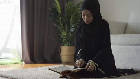 an asian muslim woman reciting salah or salat al-fatiha passage of the qur'an, in a single act of sujud called a sajdah or prostrations at home