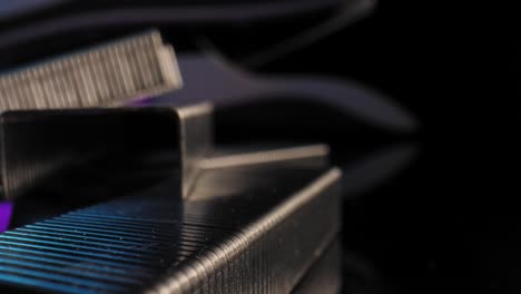 an extreme close up of blocks of staples with a stapler in the background illuminated by a purple and blue light with a black background