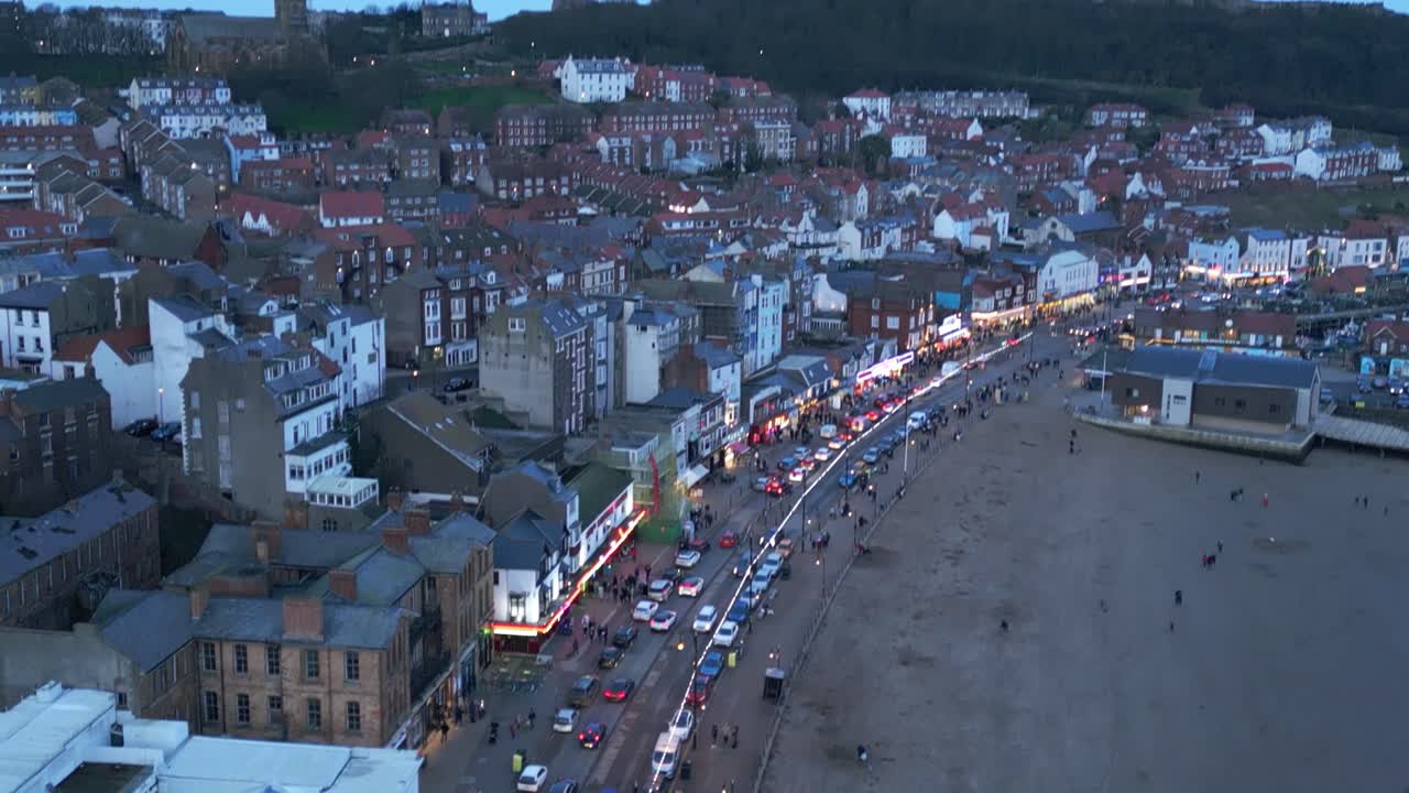 drone aéreo de arriba hacia abajo disparado sobre restaurantes concurridos a lo largo de la playa en la ciudad de scarborough, north yorkshire, inglaterra durante la noche