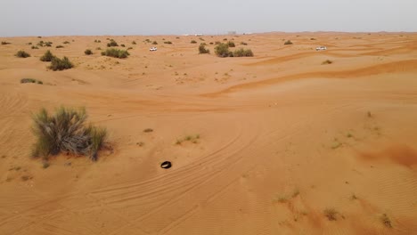 Drohnenschuss-Fliegt-über-Die-Wüste-Von-Dubai,-Während-In-Der-Ferne-Ein-Fahrzeug-Fährt