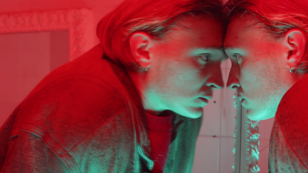 빨간 빛을 가진 방에서 거울을 보는 사람