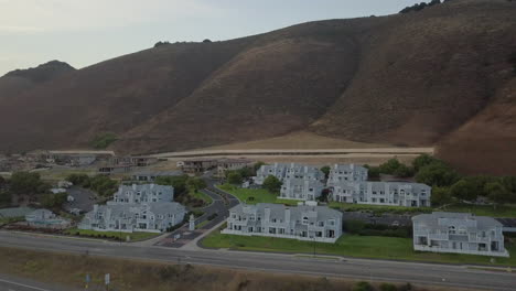 drone shot slowly flying over highway with large house and condo coastal neighborhood in pismo beach, ca