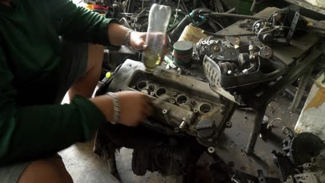 a mechanic cleaning the parts of an automobile with a brush and some oil in a machine shop in bangkok, thailand