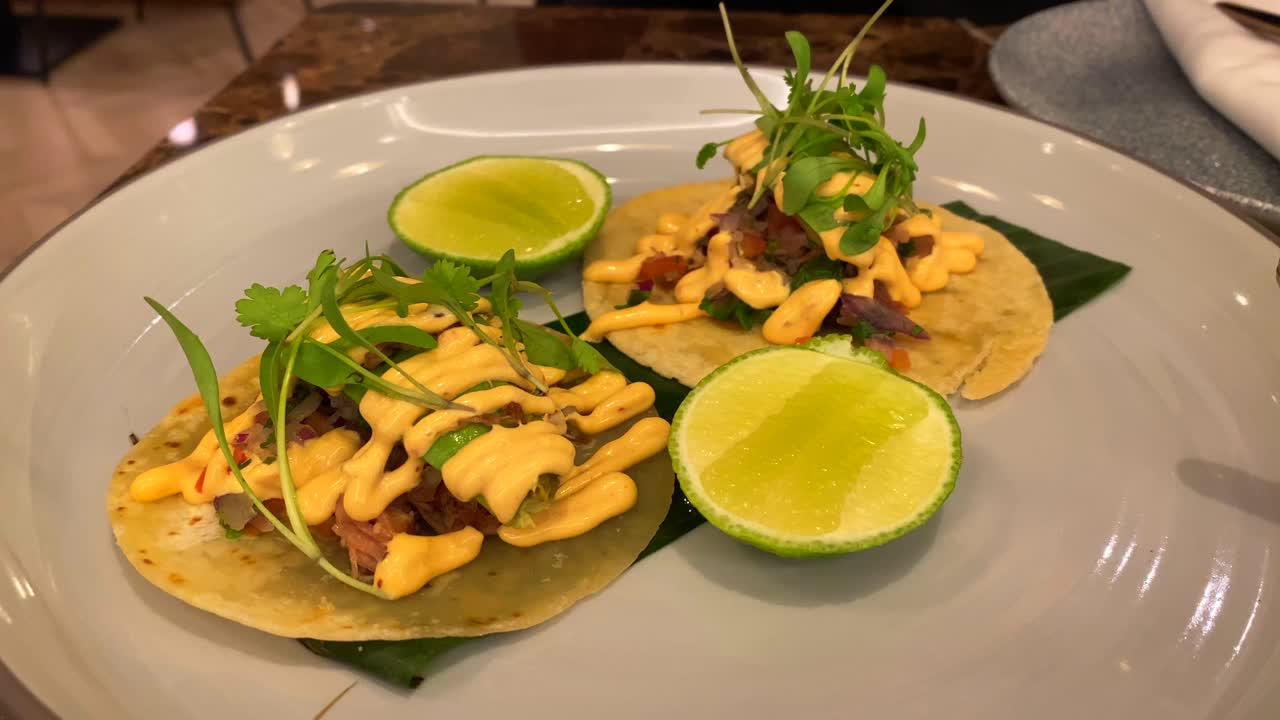 Langsomt tilberedte mexicanske cochinita pibil tacos med mikrogrønt, avocado og lime, traditionelle velsmagende autentiske svinekød tacos, 4K optagelse