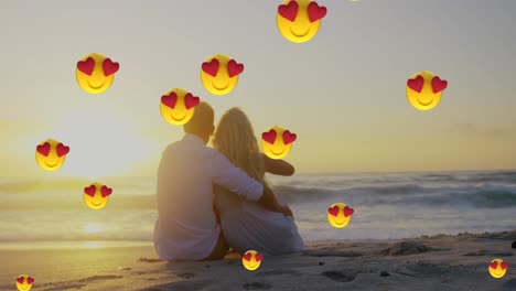 multiple heart eyes face emoji floating against couple embracing each other at beach