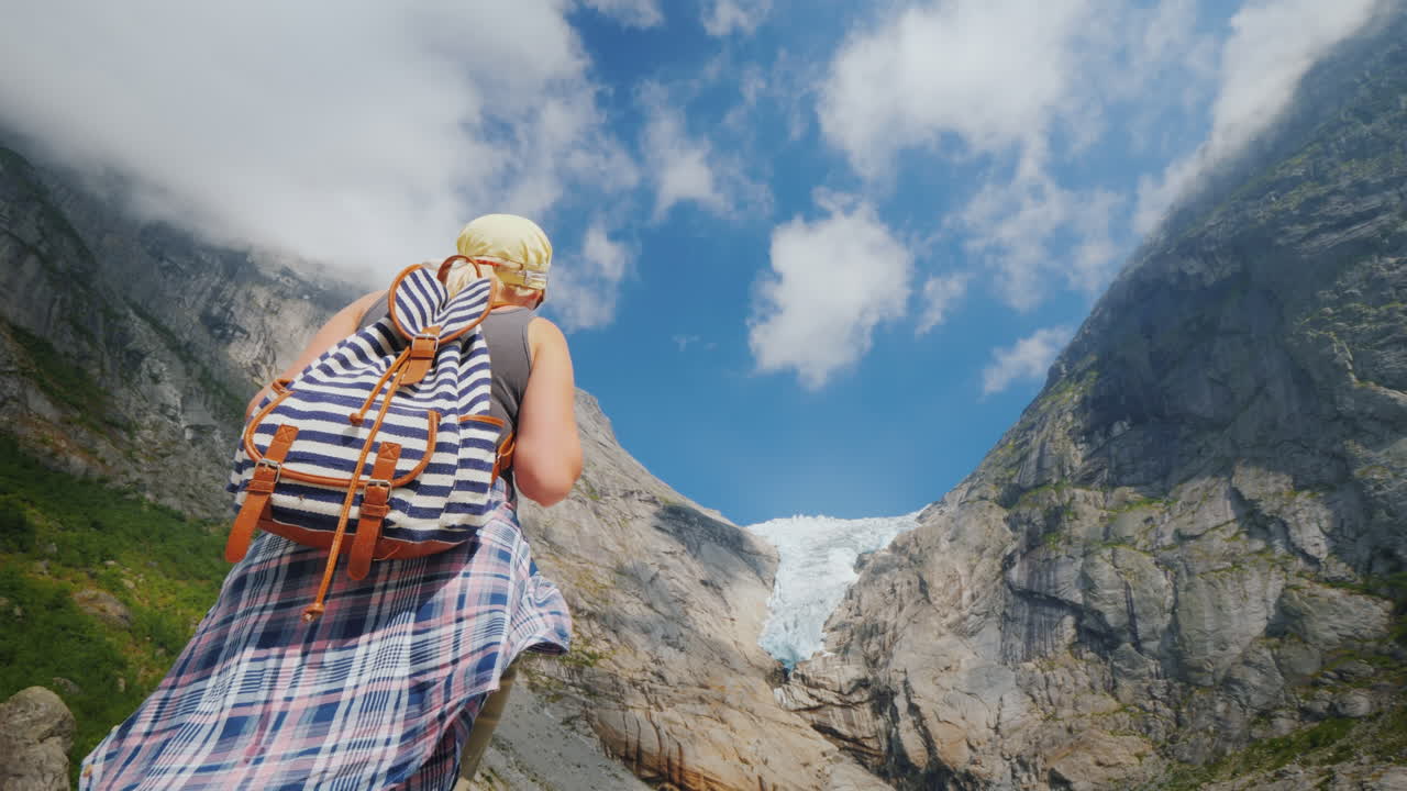 una mujer activa y exitosa se para en una roca mira las montañas y el glaciar en la cima