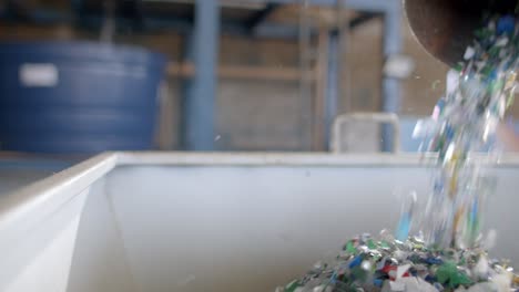 plastic flakes coming out of a tube into a container in recycling plastic facility close-up