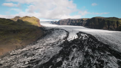elevación aérea sobre el glaciar de islandia que recorre el valle de la montaña, día soleado