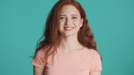 Redheaded-girl-looking-at-camera-on-turquoise-background.