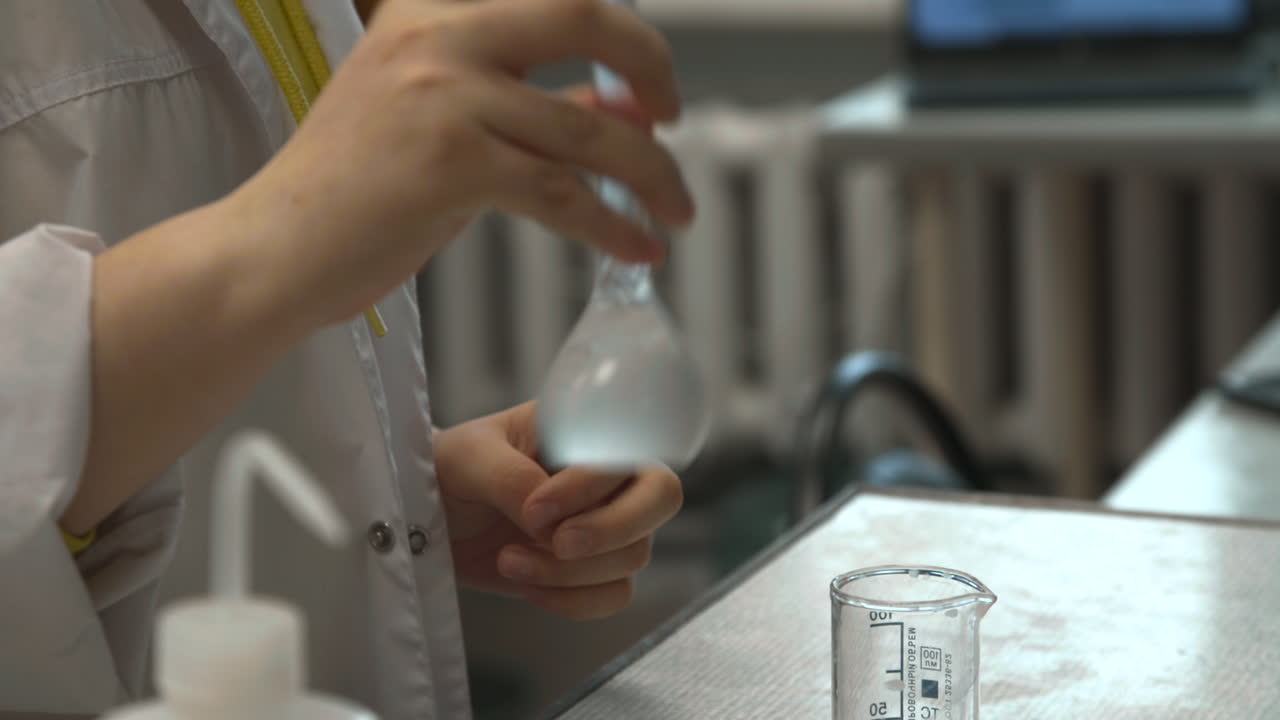 Scienziato che mescola un liquido in un matraccio tarato durante un esperimento di laboratorio
