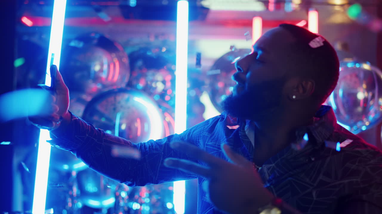 hombre afroamericano tomando fotos en una fiesta. hombre mostrando el signo de la victoria confeti