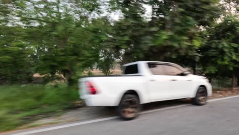 white truck driving past greenery and park area