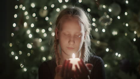 El-Niño-Sostiene-Una-Vela-Encendida-En-Sus-Manos.-Con-El-Telón-De-Fondo-De-Las-Luces-Borrosas-Del-árbol-De-Navidad.-Pide-Un-Deseo-En-Víspera-De-Navidad