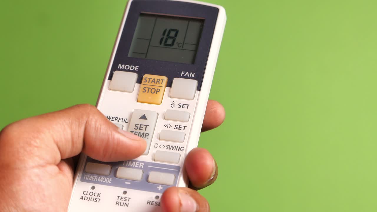 공기 조절 리모컨을 들고 있는 남자 손의 근접 사진.