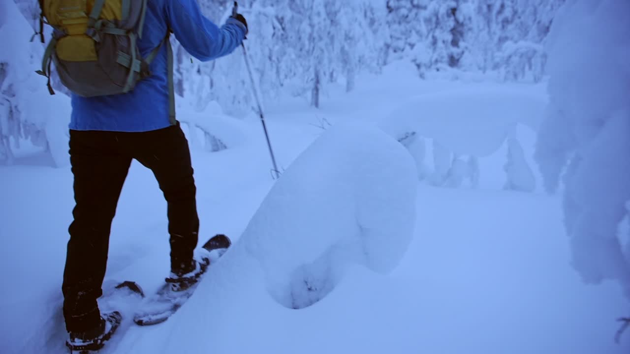 Man hiking with snow shoes in a frozen forest, in Lapland, Finland