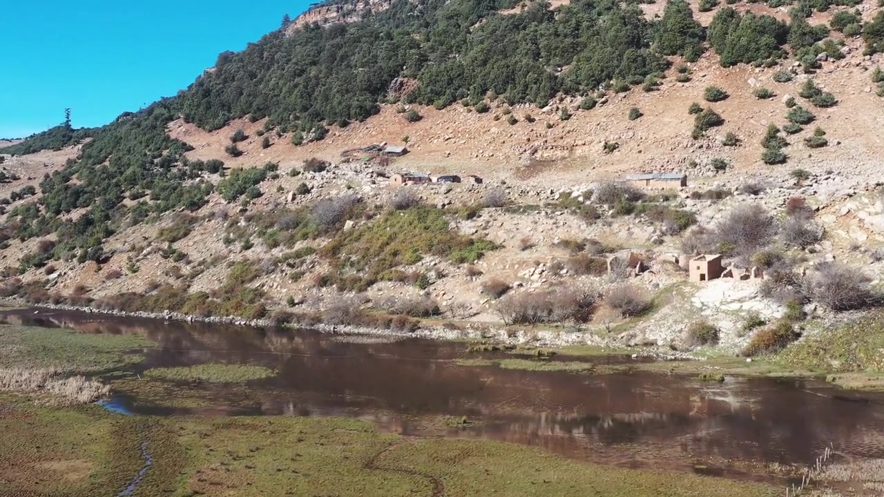 Vista de dron de un campo abierto y extenso en la campiña marroquí, rodeado de colinas y paisajes montañosos bajo un cielo azul brillante. Escenario rural tranquilo ideal para proyectos de viajes y documentales.