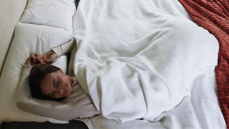 woman peacefully sleeping in cozy bed, wrapped in warm white blanket, copy space