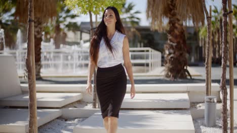 elegant young woman walking through a park
