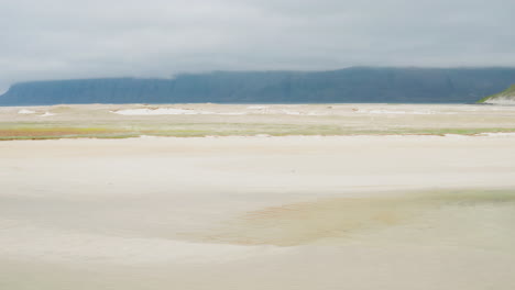 Drone-shot-sideways-dolly-with-beach,-sea-and-mountains-in-Iceland's-Westfjords-near-Patreksfjorour