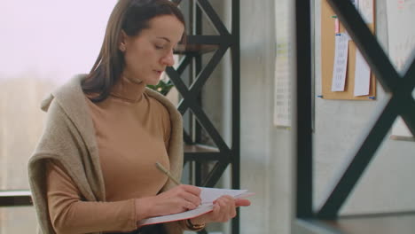 a woman designer standing at the wall attaches her ideas to the wall color selection and coloristics. choosing a color and preparing to create a design and color solution.