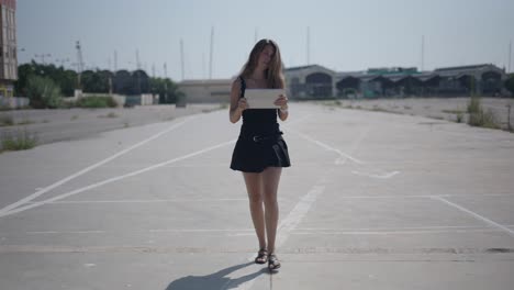 woman walking with tablet in urban parking lot