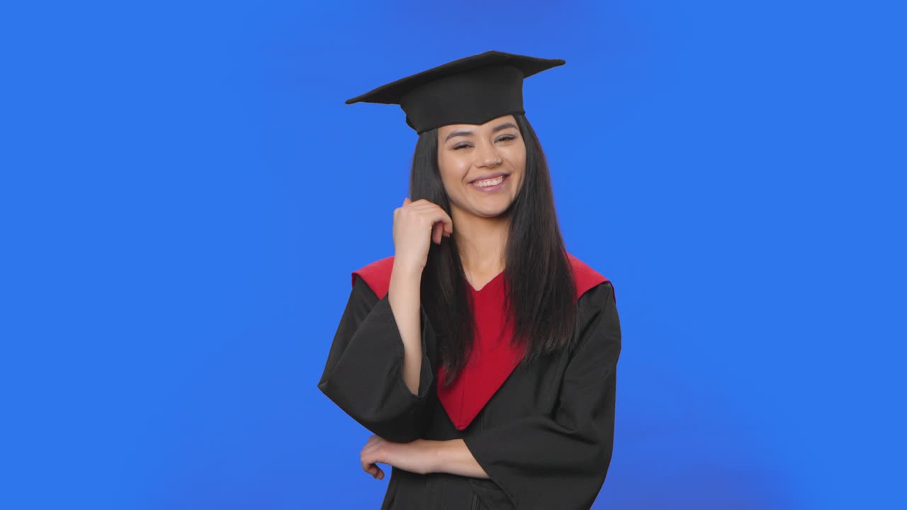 retrato de una estudiante en gorra y bata de graduación escuchando atentamente, asintiendo con la cabeza, señalando con el dedo al espectador. morena posando en el fondo de la pantalla azul. primer plano. cámara lenta lista 59.94fps